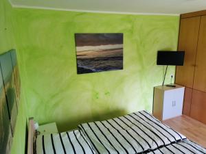 拉德贝尔根Ferienwohnung Gravemeier的绿色的客房设有一张床,墙上挂着一张照片