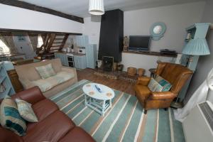 霍尔特Buttercup Cottage的客厅配有沙发、椅子和桌子