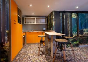 圣莫里斯堡Hotel Base Camp Lodge - Bourg Saint Maurice的橙色的厨房,配有两个凳子和一个柜台