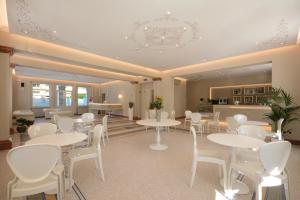 阿尔巴·阿德里亚蒂卡Residence Hotel Alba Palace的用餐室配有白色的桌子和白色的椅子