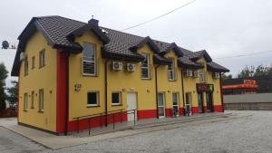 罗兹Hotelik SJ的黄色建筑,有黑色屋顶