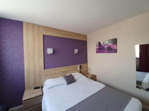 图阿尔Contact Hôtel du Relais Thouars的一间卧室配有一张床和紫色的墙壁