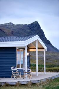 SnæfellsbærNátthagi Luxury Cottage的蓝色房子的门廊上的两把椅子