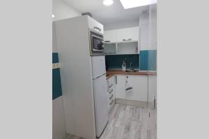 阿里纳加Apartamento Acuario的厨房配有白色橱柜和冰箱。