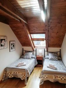 普拉德埃米塔Apartament Ca de Gallisca的阁楼卧室设有2张床和木制天花板