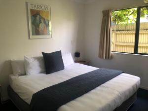 哈士汀克莱玛汽车旅馆的卧室配有一张带白色床单的大床和窗户。