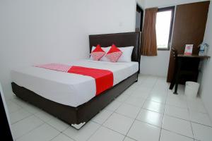 明古鲁省Super OYO 1678 Jati Exclusive Homestay的一间卧室配有红色和白色枕头的床