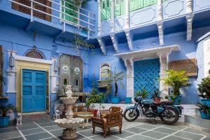 焦特布尔Heritage Gouri Haveli的一座蓝色的建筑,前面停有一辆摩托车