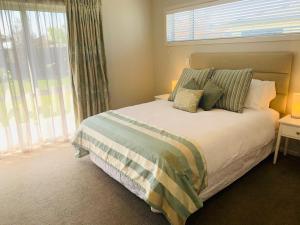 纳皮尔Hawke's Bay Haven的卧室配有带枕头的床铺和窗户。