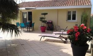 塔尔诺斯T2 Tarnos avec piscine的房屋设有一座带椅子和鲜花的庭院