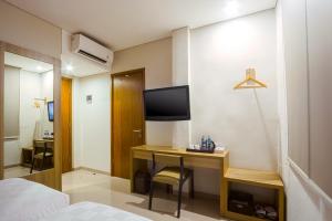 明古鲁省Cordela Inn Bengkulu的配有书桌和电视的酒店客房
