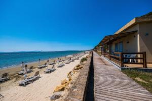 福洛尼卡Golfo del Sole Holiday Resort的海滩上,有椅子,还有一座建筑和大海