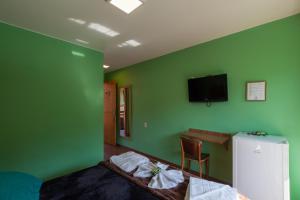 新弗里堡Pousada Zero Grau的一间卧室设有绿色的墙壁、一张床和一张书桌