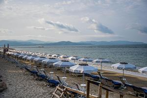 福洛尼卡Golfo del Sole Holiday Resort的海滩上的一排椅子和遮阳伞