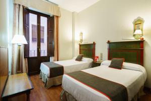格拉纳达Hotel Plaza Nueva的酒店客房设有两张床和窗户。