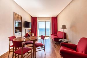 那不勒斯皇家大陆酒店的一间带红色椅子和一张桌子的客厅和一间带窗户的房间