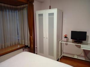 奥维多阿尔瓦雷斯旅舍的一间卧室配有一张床和一个带电视的橱柜