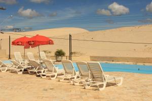 弗洛里亚诺波利斯Via Praia Apart Hotel的游泳池旁的一排椅子和一把遮阳伞