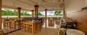 蒙纳The Lake View Munnar Resort的餐厅设有桌椅和大窗户。