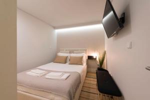 波尔图LovelyStay - Porto Peaceful Living W/ Backyard的一间白色的小卧室,配有一张床和一台平面电视