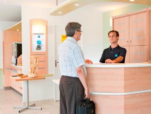 根沙根柏林艮沙宜必思快捷酒店的两个男人站在药房的柜台