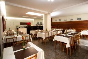 贝洛奥里藏特潘普哈公寓式酒店的餐厅配有桌椅和白色桌布
