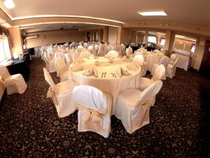 Centereach长岛石溪快捷假日酒店的宴会厅配有白色的桌子和白色的椅子