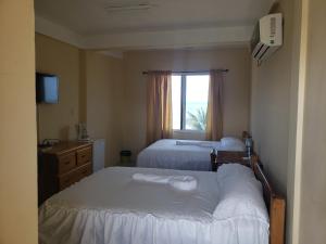 丹格里加Pal's on the beach - Dangriga, Belize的酒店客房设有两张床和窗户。