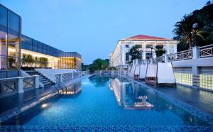 新加坡福康宁酒店的一座带遮阳伞的游泳池位于一座建筑旁边