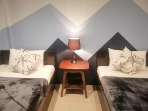 科隆Coron Ecolodge的客房设有两张床和一张带台灯的桌子。