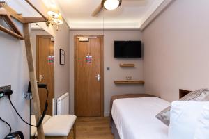 伦敦Arosfa Hotel London by Compass Hospitality的卧室配有一张床,墙上配有电视。