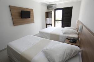 雅博蒂卡巴尔Hotel Recreio São Jorge的一间卧室设有两张床,墙上配有电视。