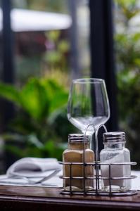 塔那那利佛拉里保迪耶里餐厅酒店的一张桌子,上面放着一杯葡萄酒和两瓶玻璃罐