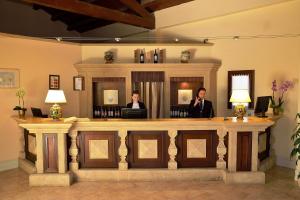 马尔萨拉Hotel Baglio Oneto dei Principi di San Lorenzo - Luxury Wine Resort的站在酒吧后面的男人和女人