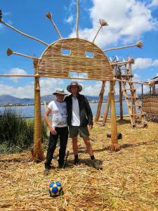 普诺Uros Lodge Lover Titiqaqa的两个人站在木结构下,带着足球球