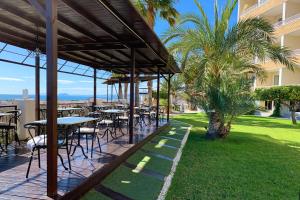 马萨龙港Ramada Resort by Wyndham Puerto de Mazarron的一个带桌椅的庭院和棕榈树