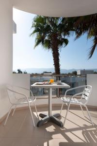 科斯镇Aegean Blu Hotel & Apartments的棕榈树阳台的一张桌子和两把椅子