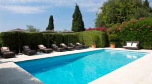 格拉斯Bastide Saint Antoine - Relais & Châteaux的花园内带躺椅和椅子的游泳池