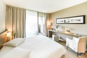 库尔农拉格里兰德斯生态酒店及伊夫黎雪Spa的卧室配有一张白色大床和一张书桌
