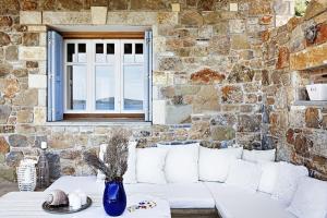 Aghios Petros AlonissosLithea Villas and Studios by the Sea的石墙前的白色沙发,带窗户