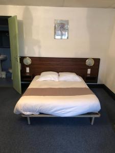 Saint-PaulienHôtel des voyageurs的一间卧室配有一张大床和木制床头板