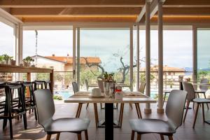 巴多利诺Hotel Villa Olivo Resort 3S的一间带桌椅和窗户的用餐室