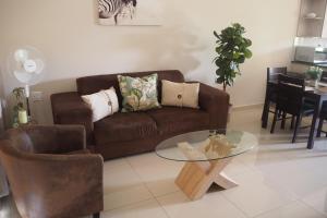 博克斯堡OR Tambo Self Catering Apartments, The Willows的客厅配有棕色沙发和玻璃桌