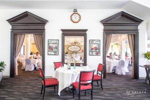 佛统The Royal Gems Golf Resort的餐厅设有白色桌子、红色椅子和时钟