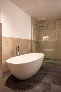 卡普尔LUVA Resorts Kappl - Chalet K的带淋浴的浴室内的白色大浴缸