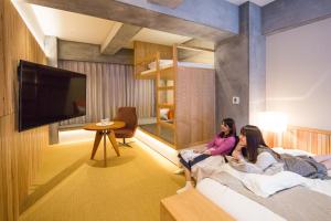 东京Sakura Cross Hotel Tokyo Kayabacho的两个女孩坐在旅馆房间的床边