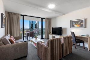 布里斯班Oaks Brisbane River City Suites的带沙发、书桌和电视的客厅