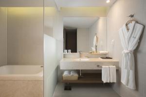 西归浦市大自然隐藏悬崖酒店 的一间带水槽、浴缸和镜子的浴室