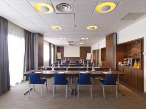 布拉尼亚克快捷假日图卢兹机场酒店的一间会议室,配有长桌子和蓝色椅子