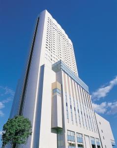 名古屋名古屋ANA皇冠假日酒店的一座高大的白色建筑,前面有一棵树